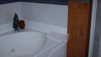 A bathroom with a white bathtub, a wooden door, and a floral-patterned wall.
