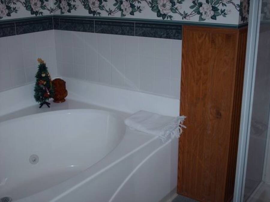 A bathroom with a white bathtub, a wooden door, and a floral-patterned wall.