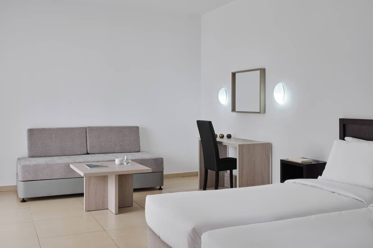 Ein modernes Hotelzimmer mit Bett, Sofa, Schreibtisch und Stuhl.
