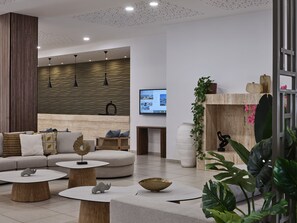 Ein modernes Interieur mit einer Couch, runden Tischen, einem Kamin und einem Fernseher.