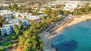 A coastal resort with multiple white buildings, a sandy beach, and a clear blue sea. - Atlantica Callisto (Ayia Napa)