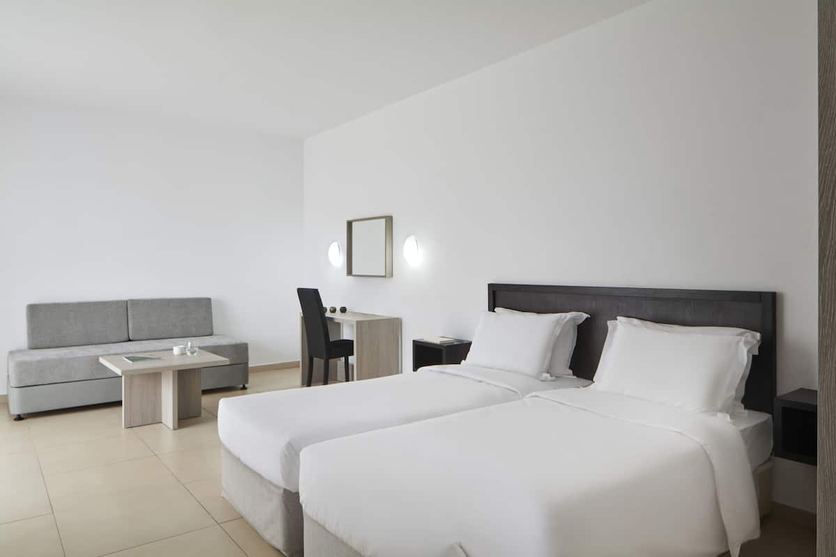 Ein modernes Hotelzimmer mit einem großen Bett, einer Couch, einem Schreibtisch und einem Stuhl.
