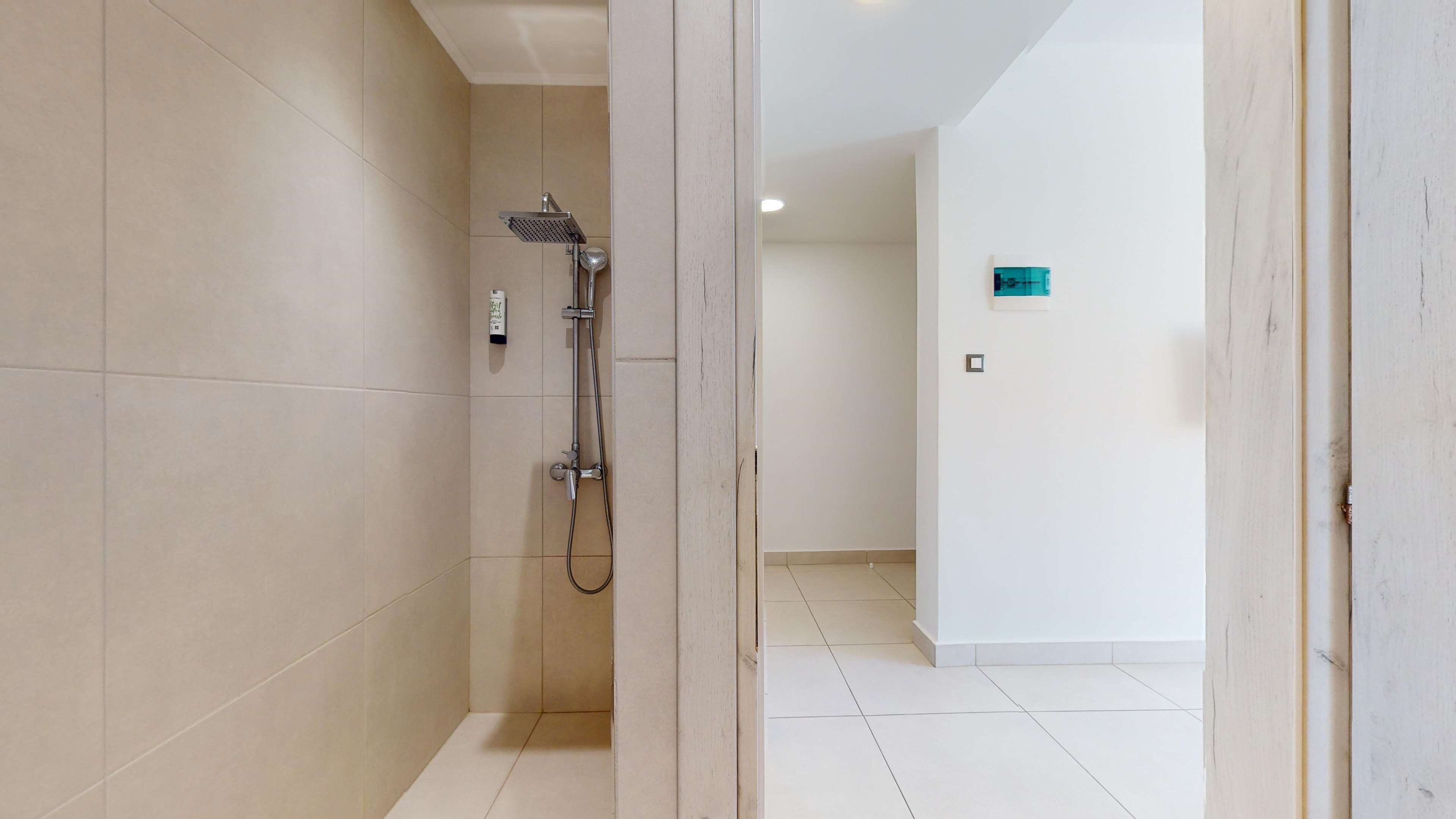 Un baño moderno con ducha, paredes con azulejos y un diseño limpio y minimalista.