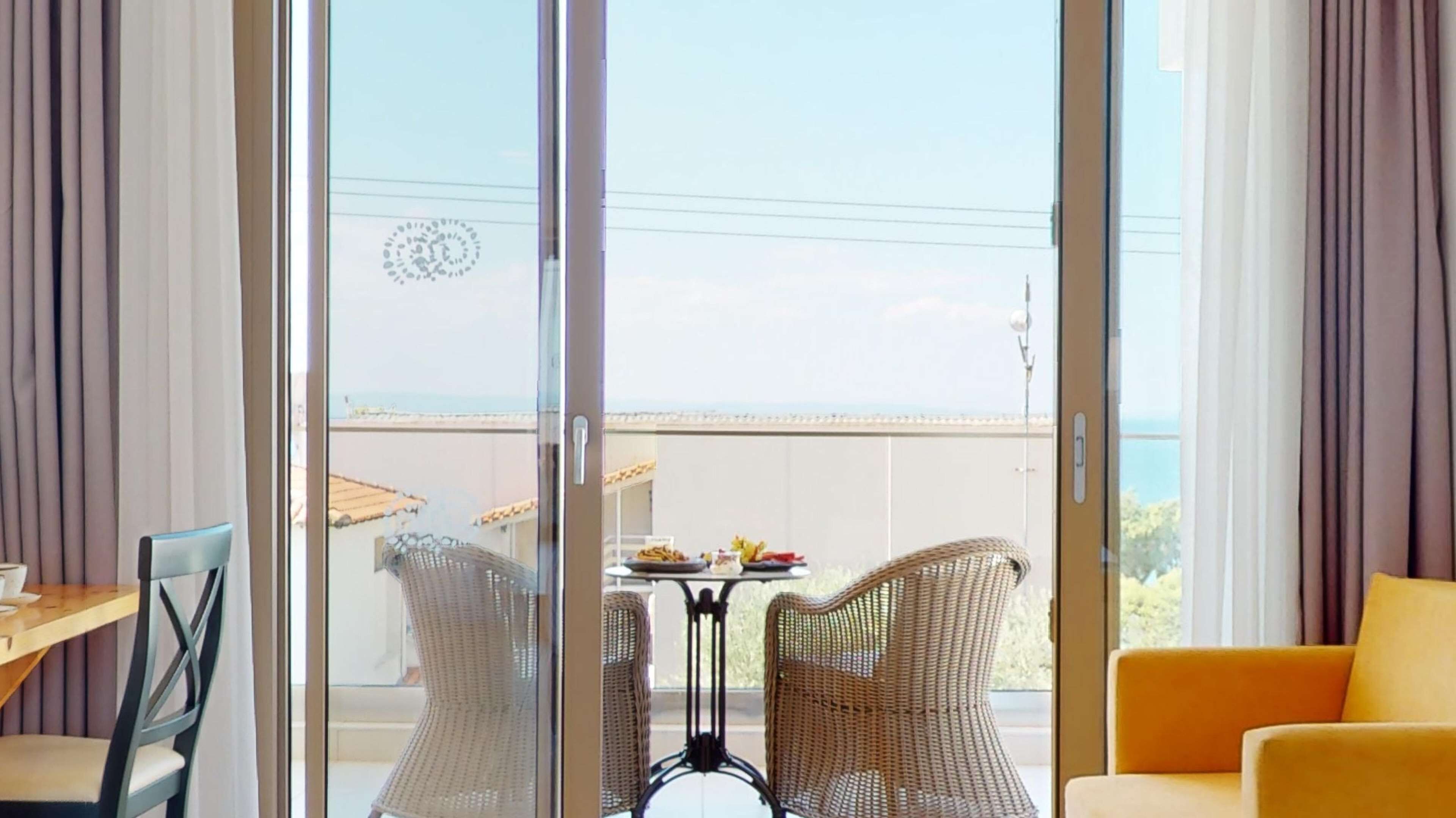 A room with a sliding glass door leading to a balcony with a table and chairs.