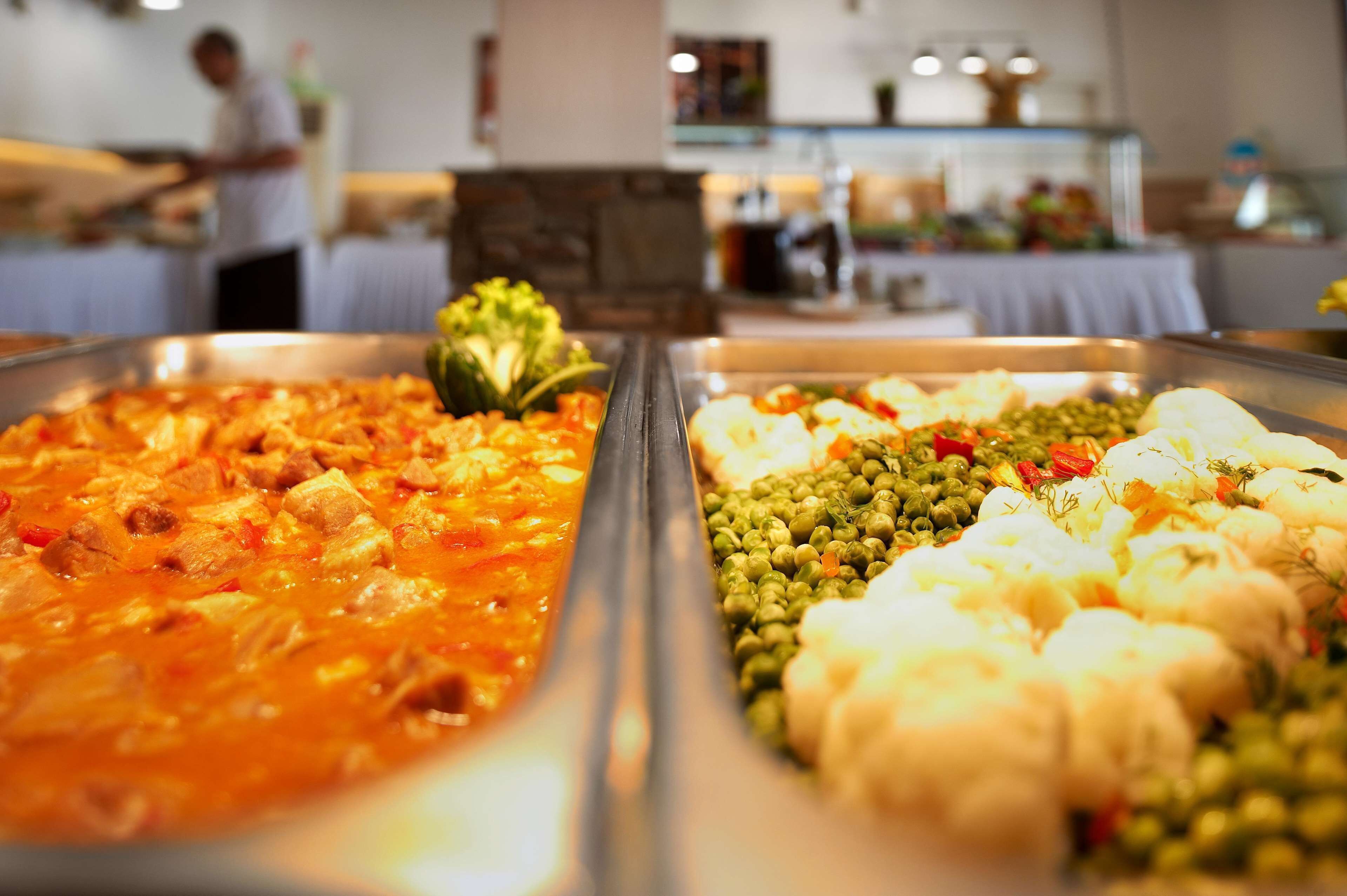 A buffet with various dishes including pasta, vegetables, and meats.