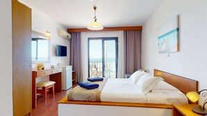 A hotel room with a bed, a desk, a chair, a TV, and a balcony with a view. - Acrotel Elea Beach (Sithonia)