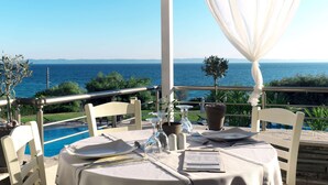 A table set for two with a view of the sea, a pool, and greenery. - Acrotel Elea Beach (Sithonia)