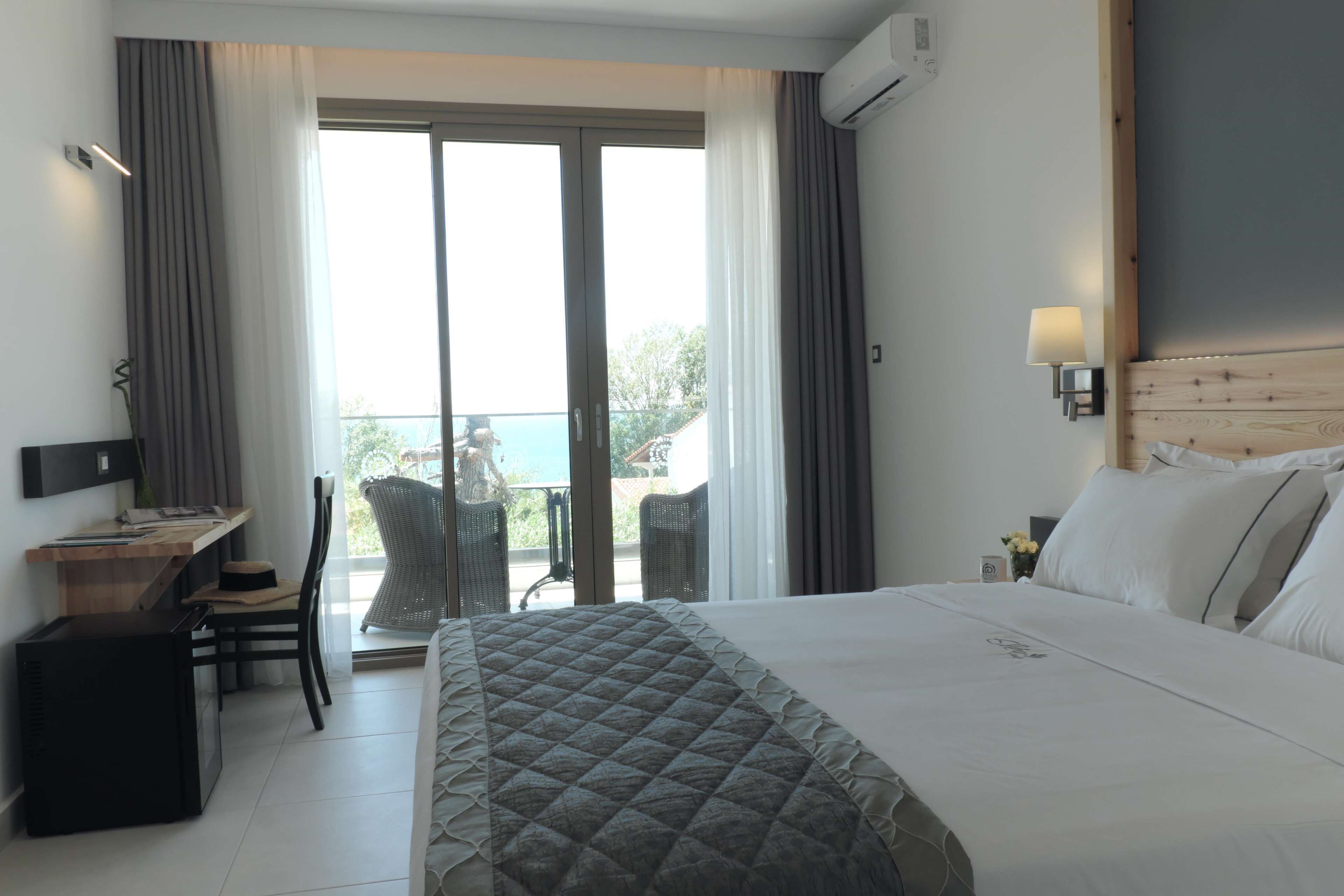 A hotel room with a bed, a desk, a chair, and a balcony with a view.