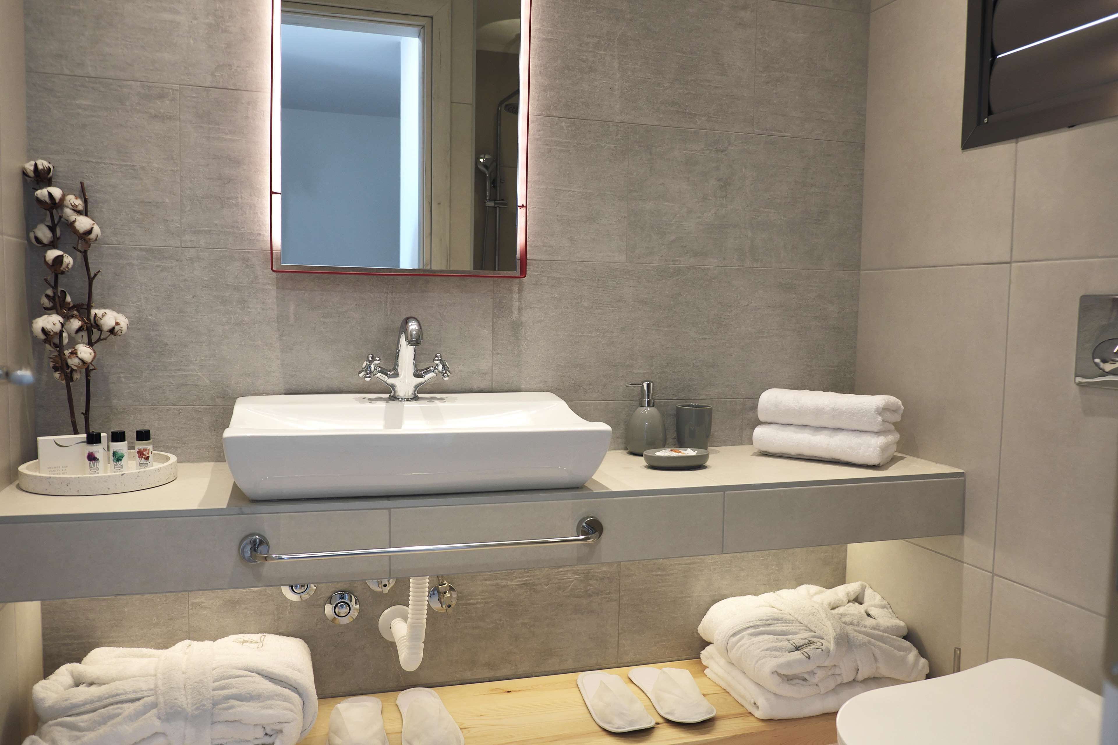 A modern bathroom with a large sink, a towel rack, and a mirror.