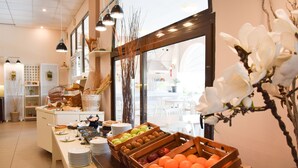 A buffet area with various fruits and dishes, wooden crates, and a view of the dining area through a large window. - Acrotel Elea Beach (Sithonia)