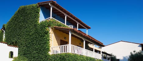 A house with a sloped roof, a balcony, and ivy-covered walls.