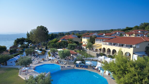 A resort with multiple swimming pools, outdoor seating areas, and a view of the sea. - Acrotel Elea Beach (Sithonia)