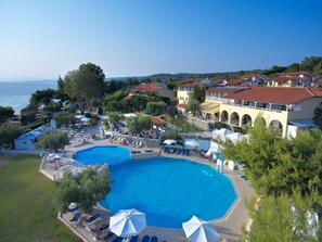 A resort with multiple swimming pools, outdoor seating areas, and a view of the sea. - Acrotel Elea Beach (Sithonia)