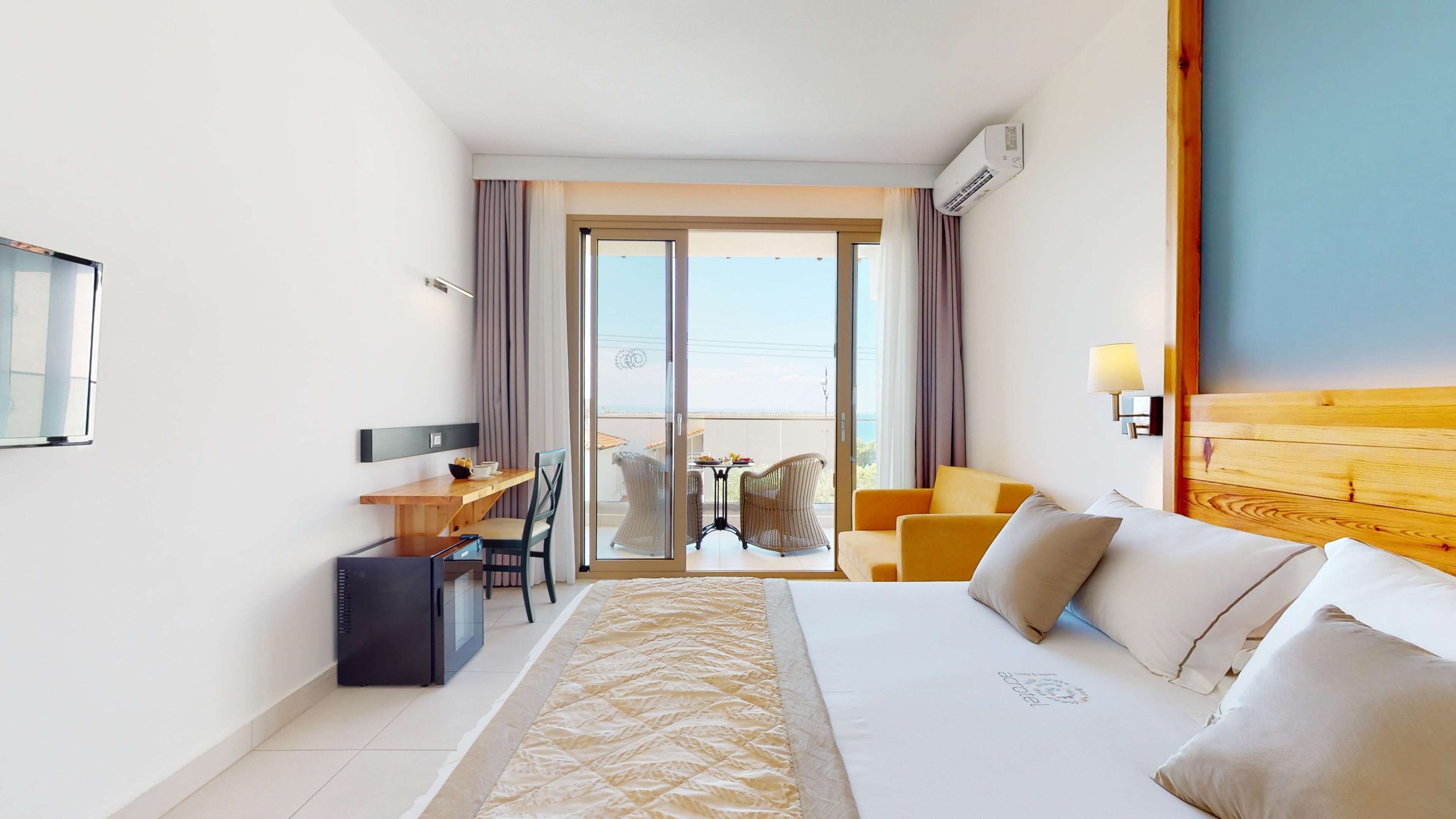 Una camera d'albergo con un letto, una scrivania con una sedia, un tavolino con sedie e una vista attraverso una porta di vetro.