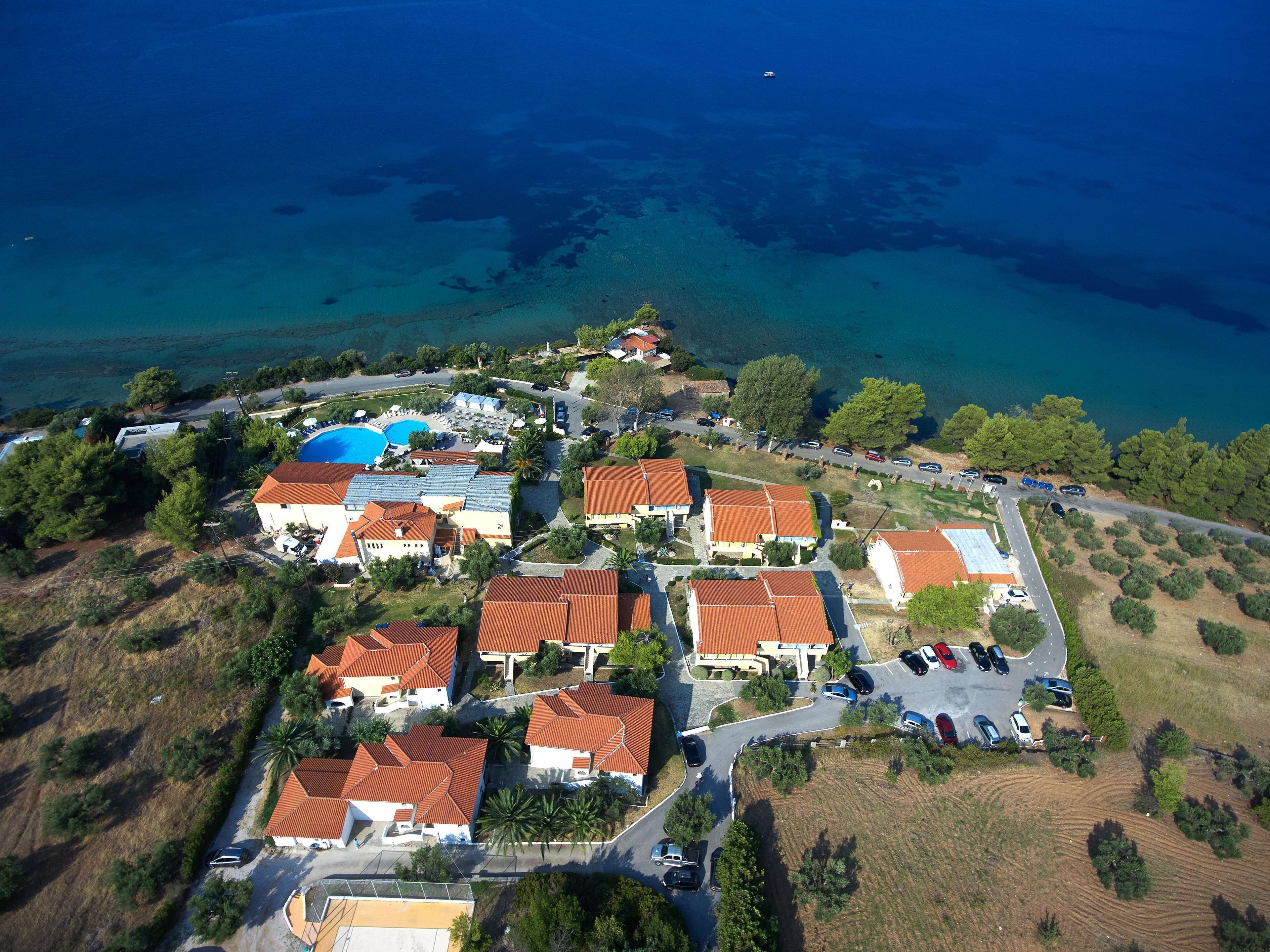 Vista aérea de una zona residencial costera con casas, una piscina y una carretera.