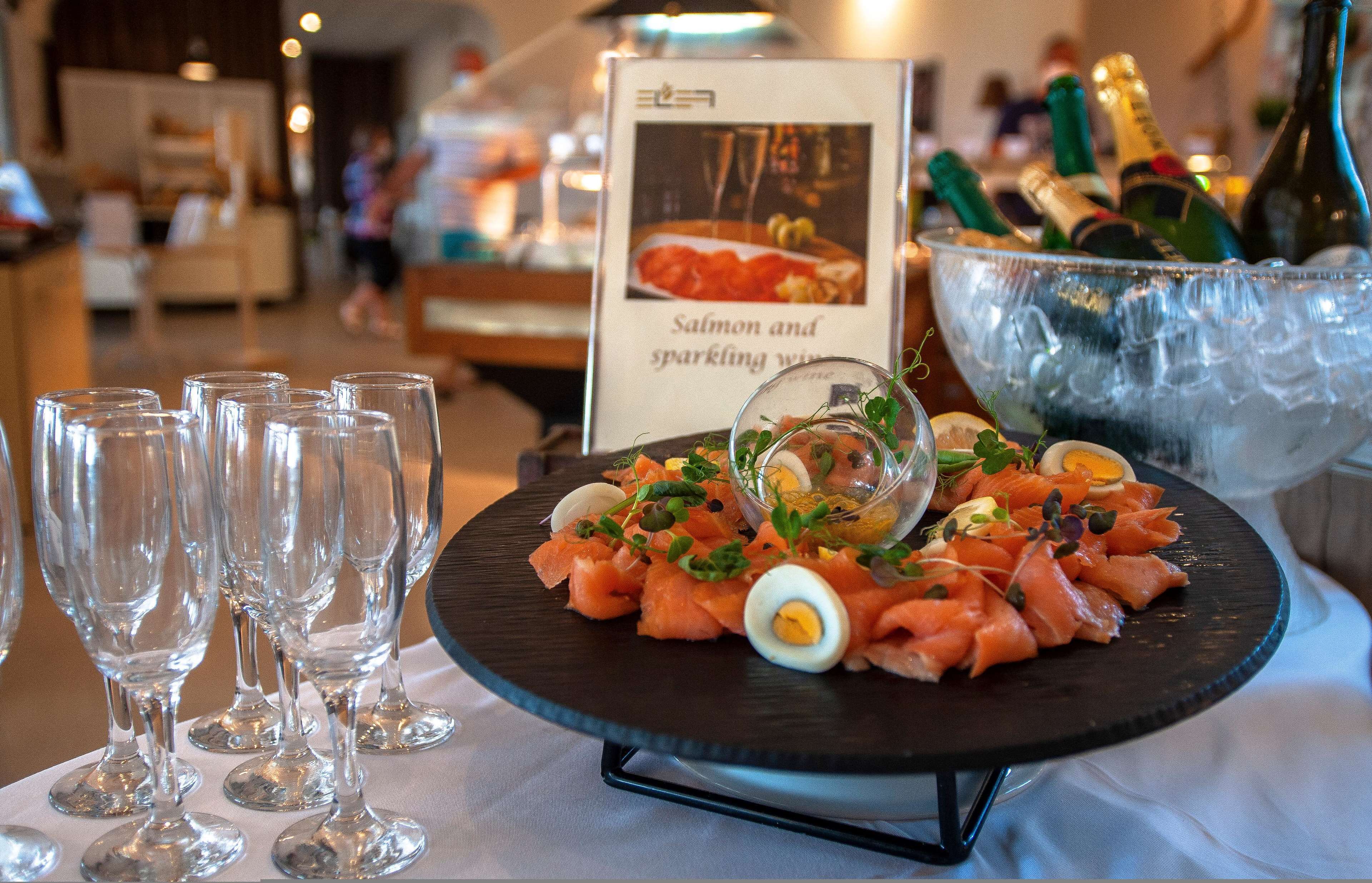 Un tavolo per buffet con un segnale che indica salmone e vino spumante, una ciotola di ghiaccio e diversi bicchieri.