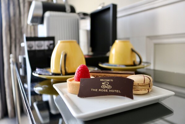 A dessert tray with a chocolate sign, a strawberry, and macarons on a white plate.