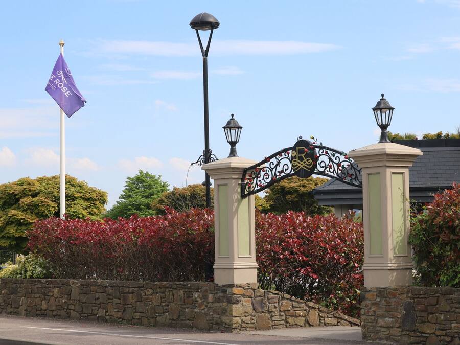 A stone wall with a wrought iron gate, a flag, and a street lamp.