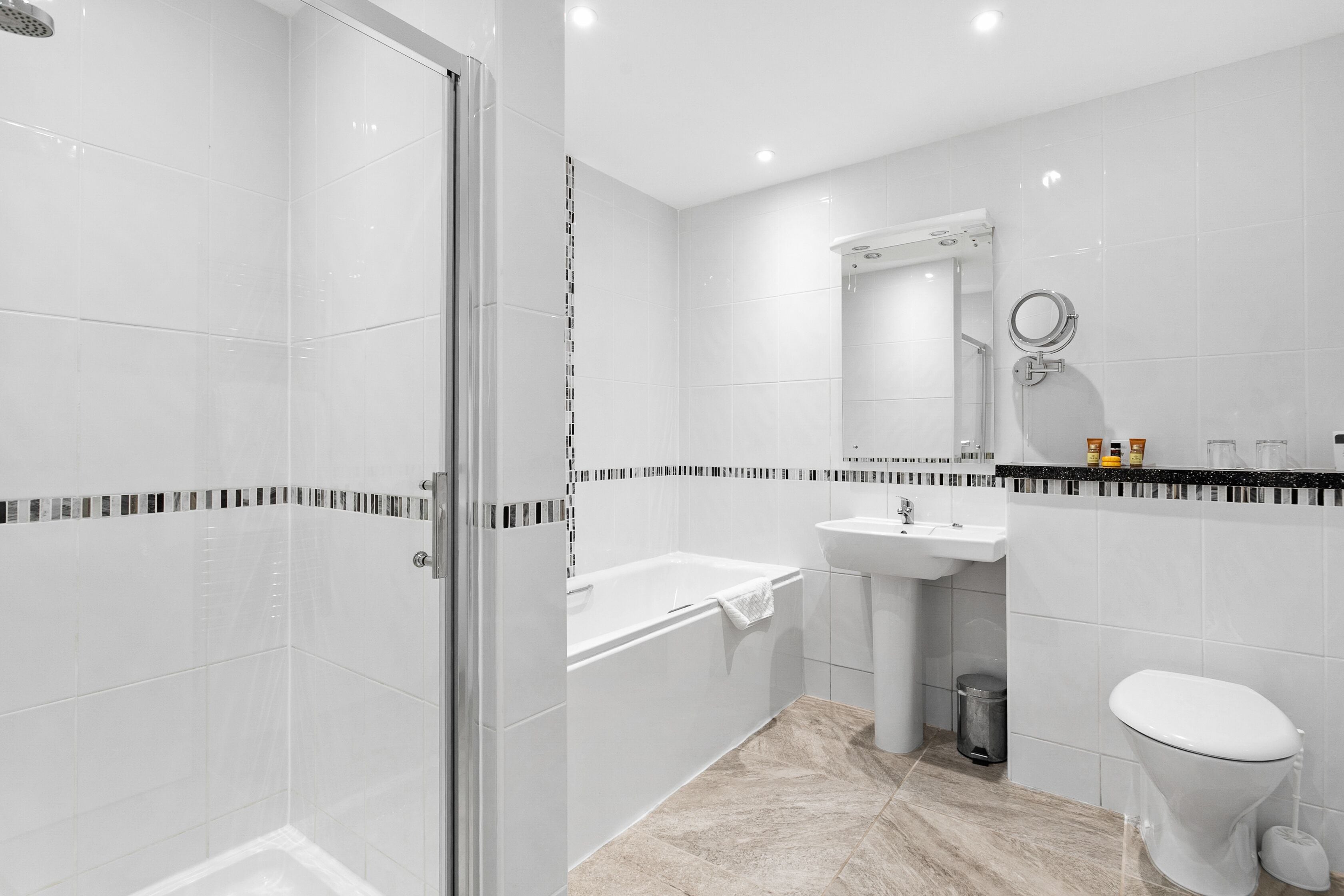 A modern bathroom with a glass-enclosed shower, a bathtub, a sink, and a toilet.