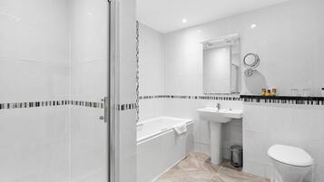 A modern bathroom with a glass-enclosed shower, a bathtub, a sink, and a toilet.