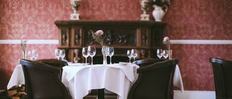 A dining area with a round table set for four, surrounded by dark wooden chairs.