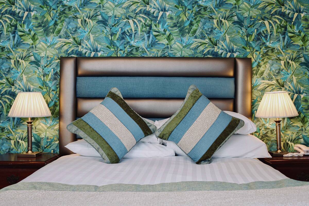 A neatly made bed with striped pillows, a headboard, and two bedside lamps.