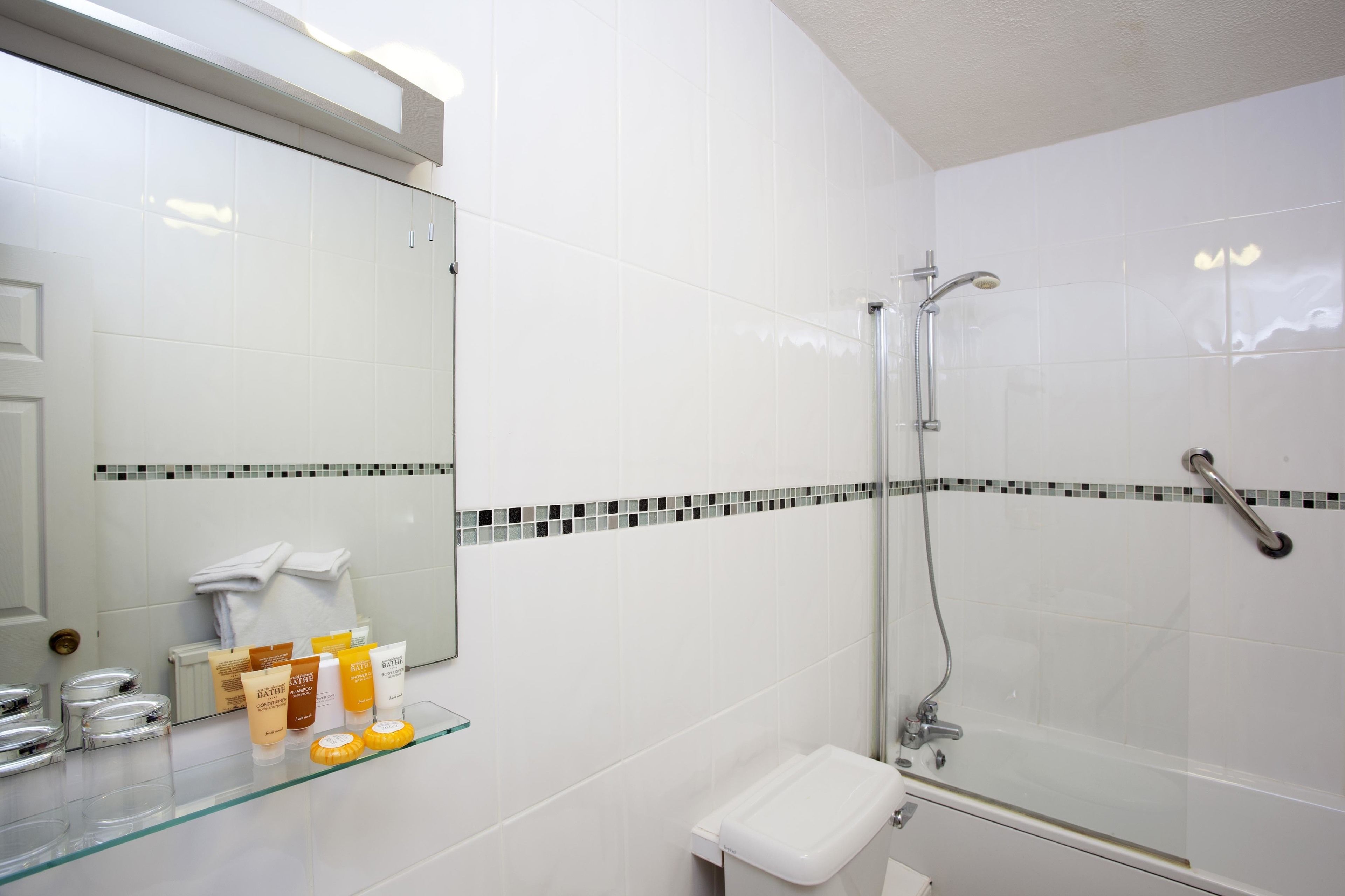 A modern bathroom with a glass shower enclosure, a white sink, and a mirror above it.