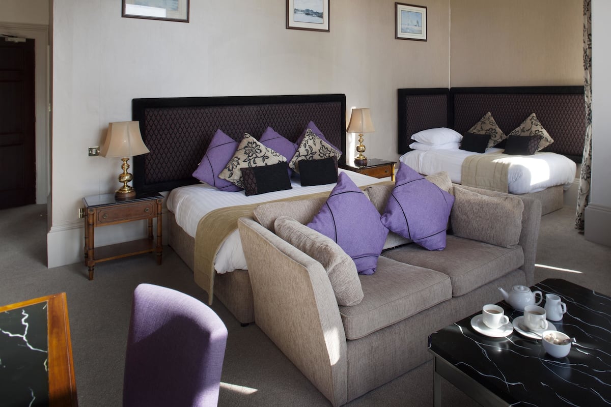 A hotel room with two beds, a sofa, a coffee table, and a chair.