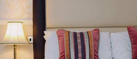 A neatly made bed with white linens and a decorative pillow with stripes.