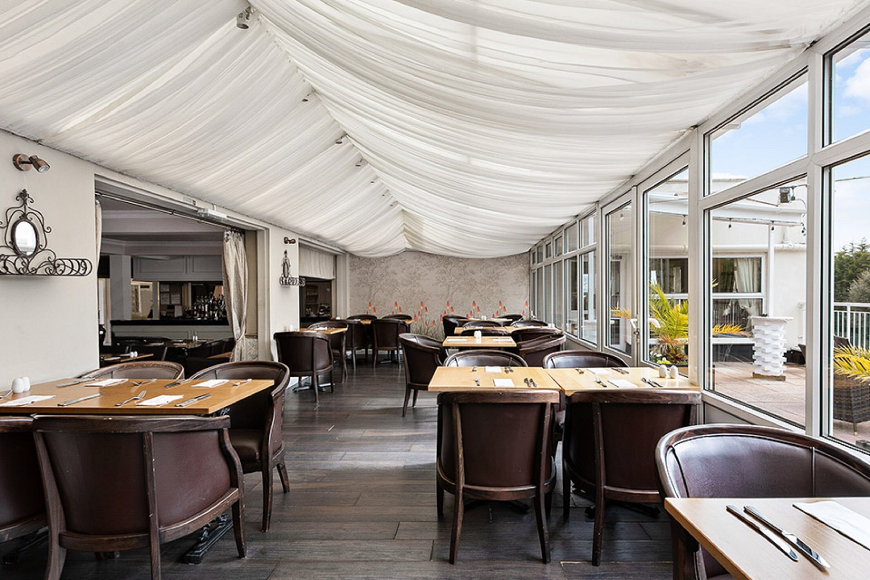 Un restaurant avec des tables et des chaises, un plafond blanc et de grandes fenêtres.