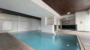 An indoor swimming pool with a tiled floor, a wooden ceiling, and a sign indicating a pool depth of 1.4 meters. - Abbey Sands Hotel (Torquay)