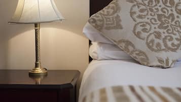A neatly made bed with a patterned pillow and a bedside lamp on a wooden nightstand.