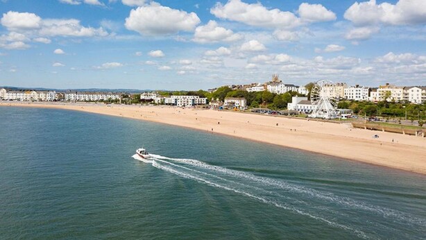 A coastal town with a sandy beach, a Ferris wheel, and a boat on the water. - Abbey Sands Hotel (Torquay)