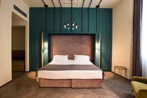 Camera d'albergo moderna con un letto grande, pareti color petrolio e un lampadario dal design originale.