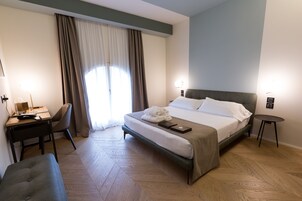 Camera d'albergo con un letto, una scrivania, una sedia, un tavolino e una panca.
