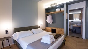 A modern hotel room with a large bed, bedside tables, a wardrobe, and a bathroom visible through an open door. - Hotel Silla (Florence)