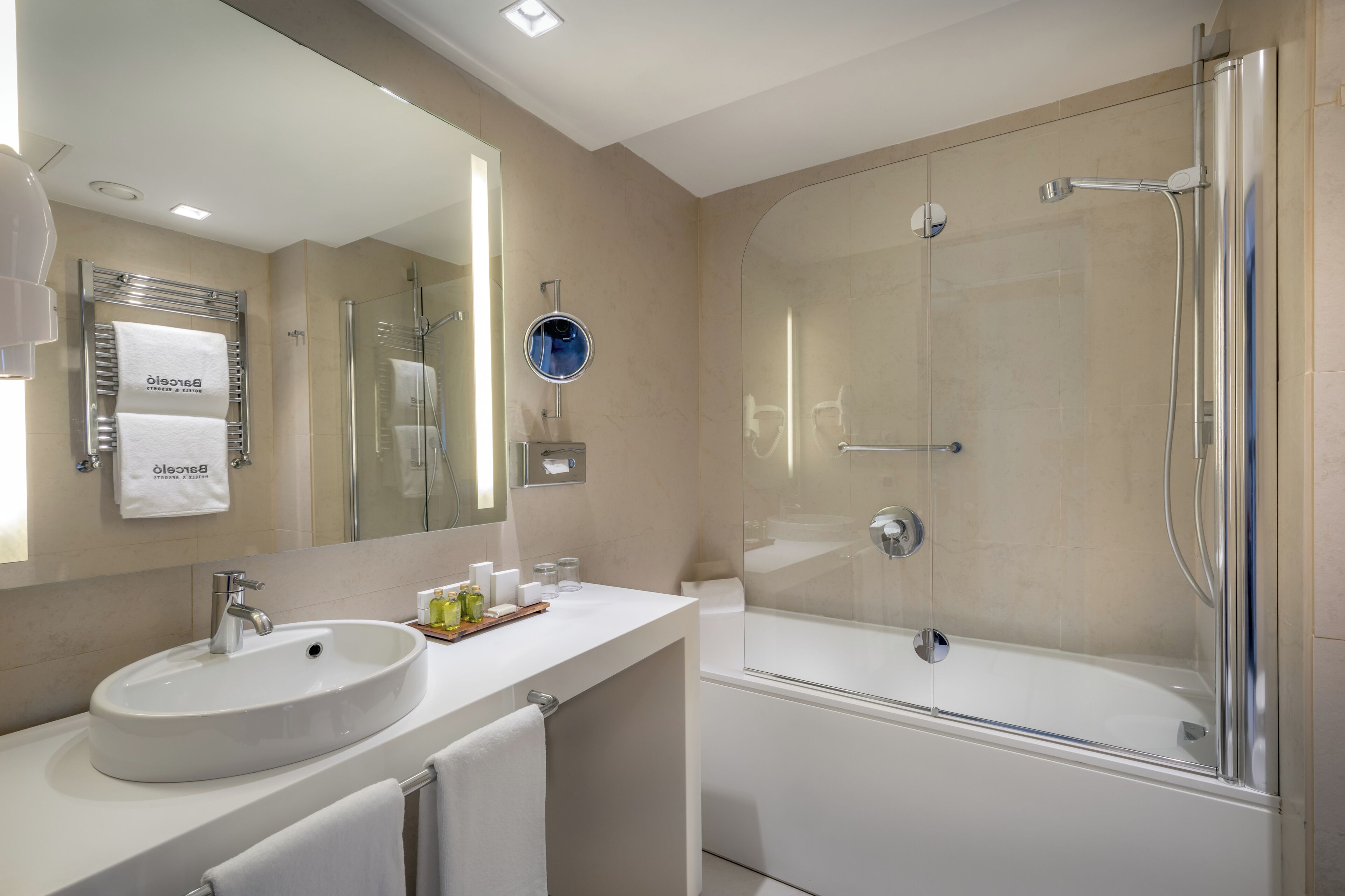 Un baño moderno con lavamanos, espejo y ducha con mampara de vidrio.
