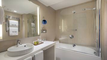Un baño moderno con lavamanos, espejo y ducha con mampara de vidrio.