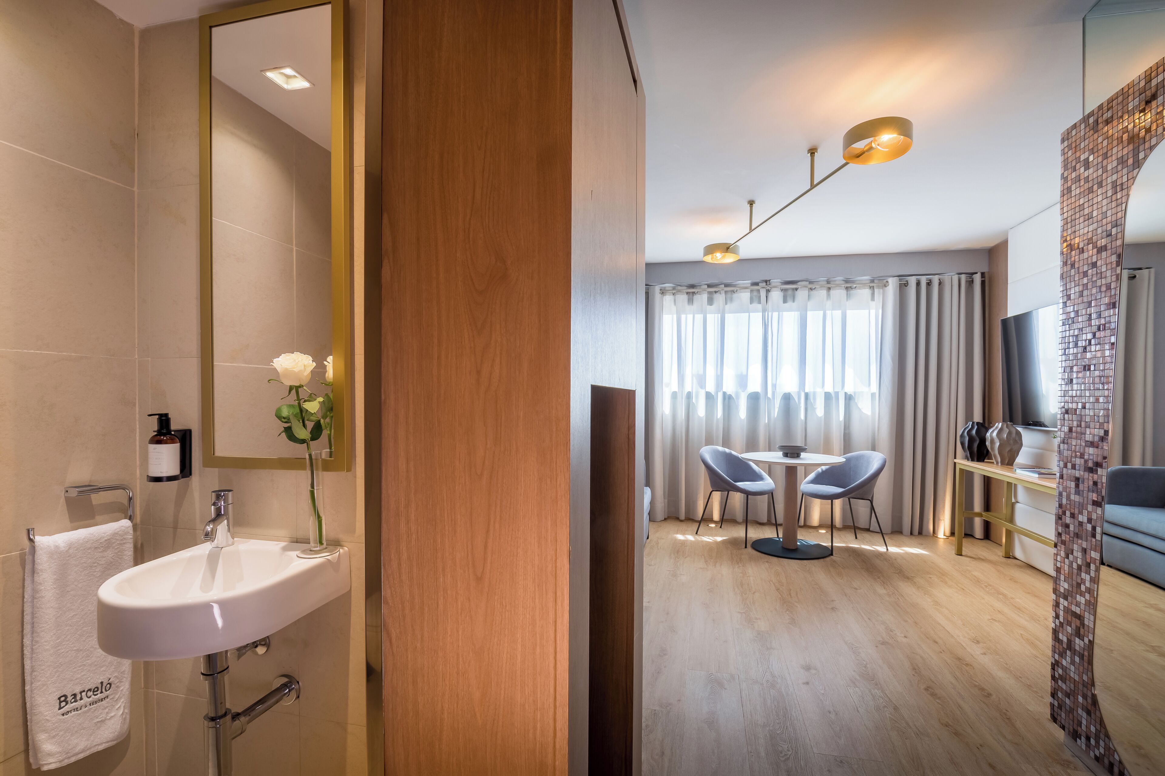 Een moderne badkamer met een witte wastafel, spiegel en een handdoek met 'Barcelo' branding.