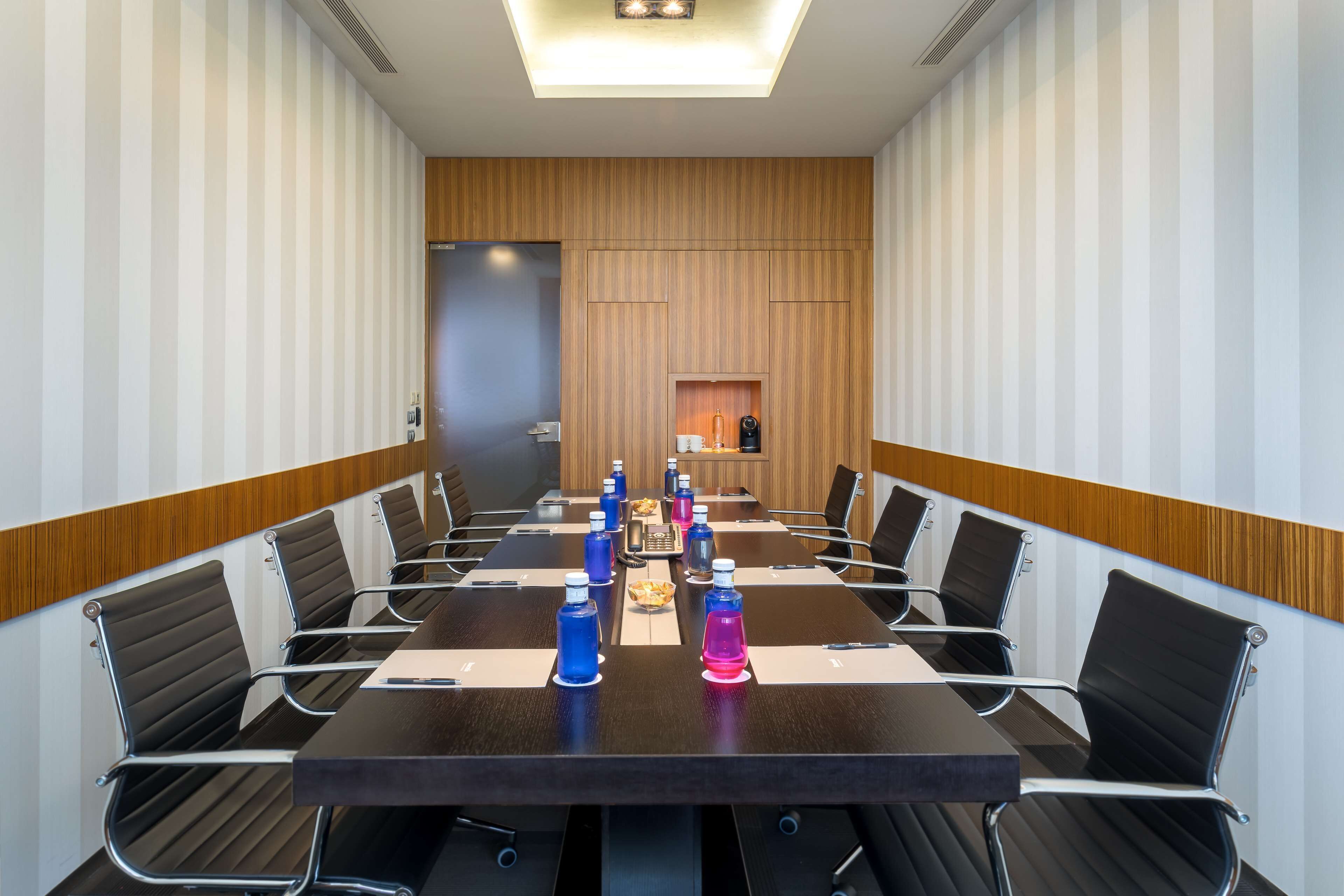 A conference room with a long table, black chairs, and water bottles.