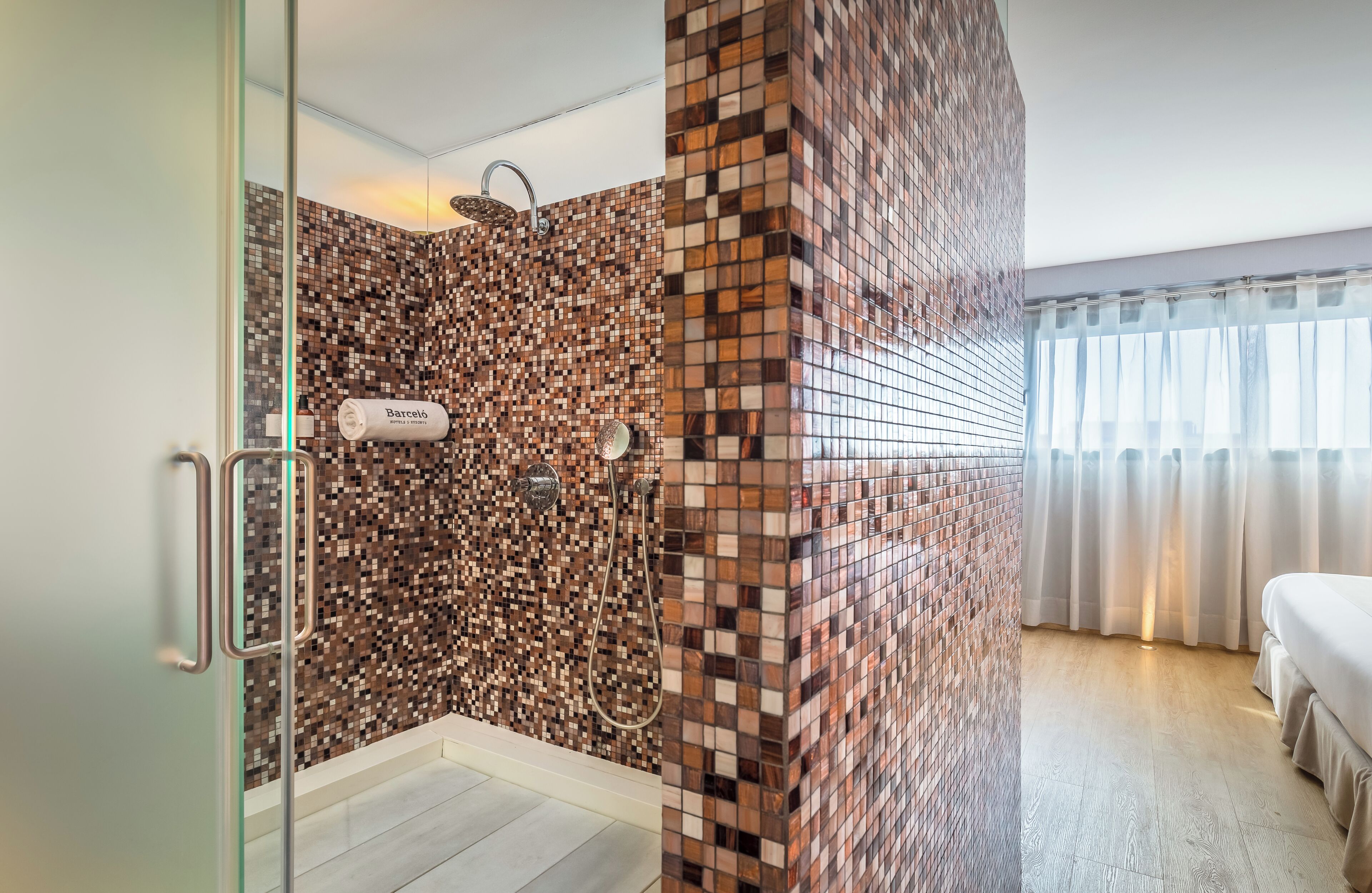 A modern bathroom with a mosaic tile shower wall, a glass shower enclosure, and a visible towel rack.