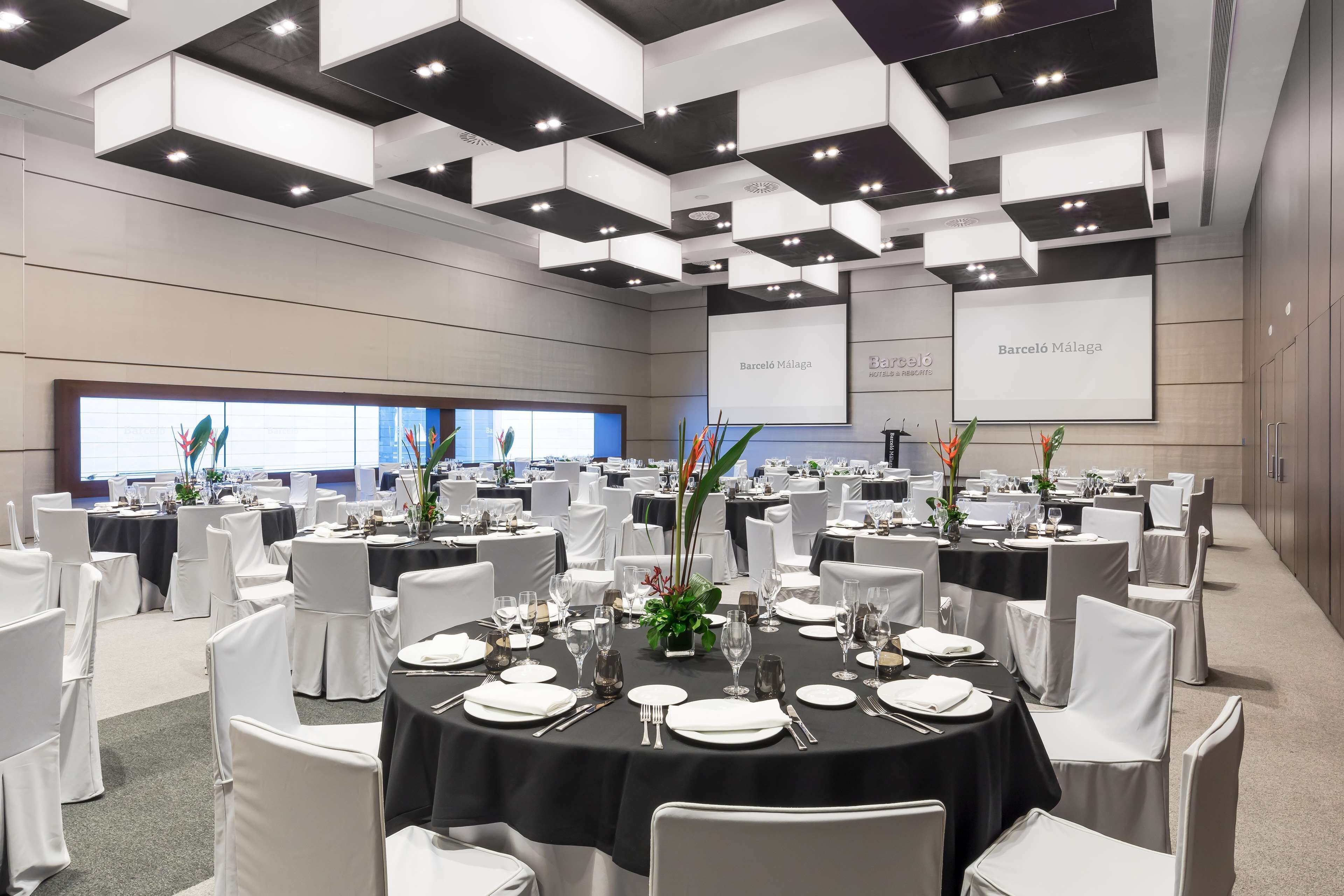 A conference room with round tables, white chairs, and black tablecloths.
