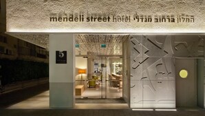 The exterior of the Mendeli Street Hotel with a modern entrance and a visible reception area inside.