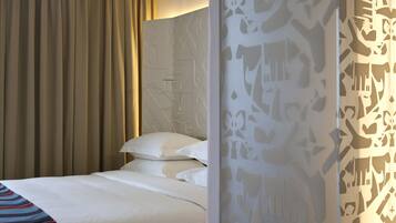 A hotel room with a bed, curtains, and a patterned wall.