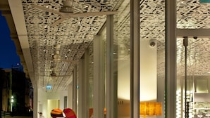 A modern interior with a patterned ceiling, glass walls, and contemporary furniture.