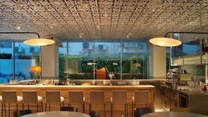 A modern bar area with a wooden counter, bar stools, and pendant lighting.