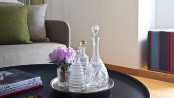 A tray with glassware and a vase of flowers on a table, with books and a bowl of nuts nearby.