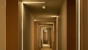 A long, narrow hallway with wooden paneling and illuminated linear lights along the ceiling.