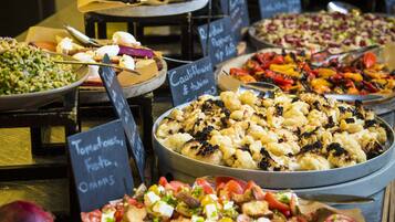 Un buffet proposant divers plats, notamment des salades, des légumes grillés et un assortiment de fromages.