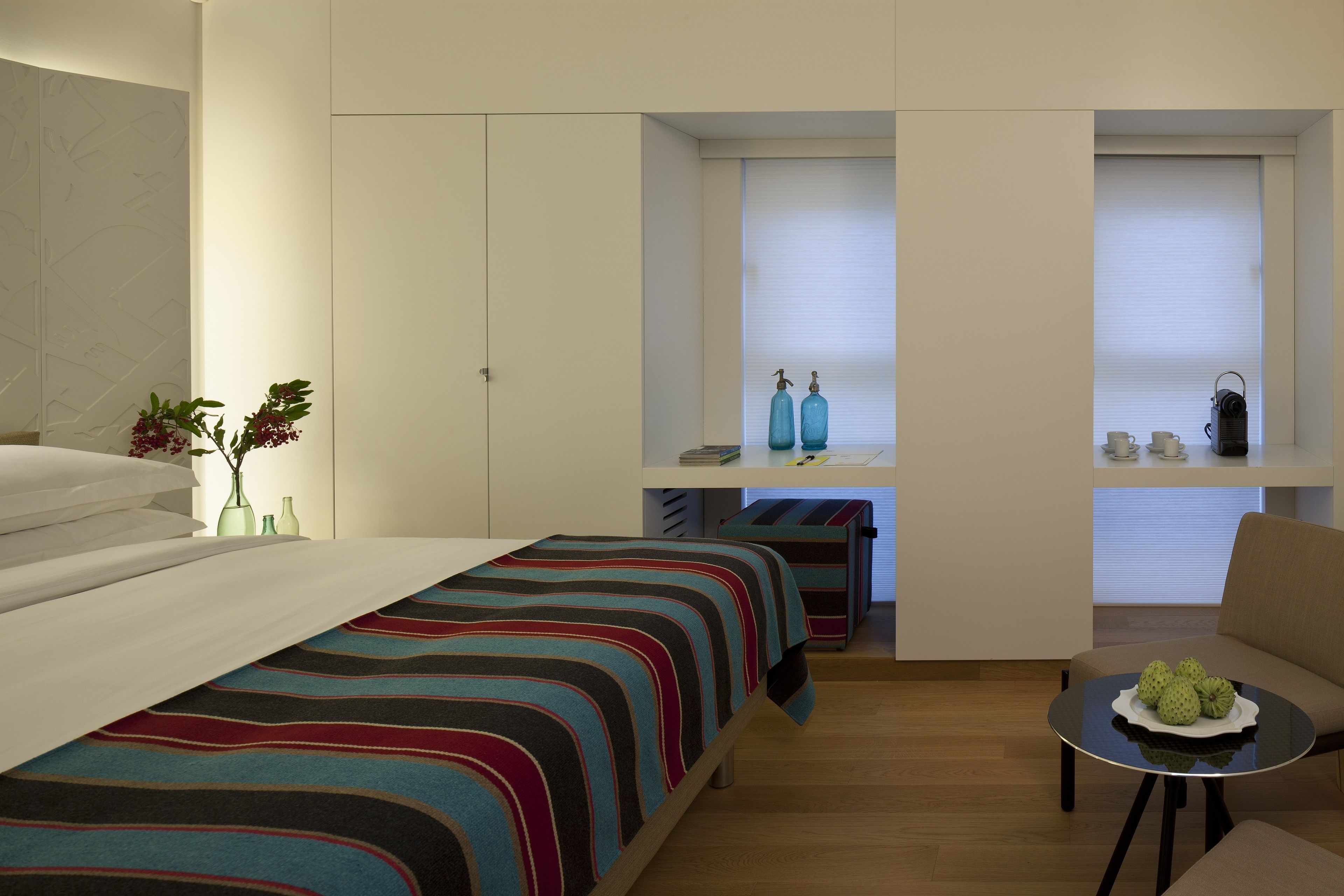 Habitación de hotel pequeña con cama, un escritorio, una silla y una mesa con fruta.